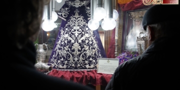 La saya restaurada de la Virgen de la Trinidad se expone en el escaparate de Ópticas Fernández